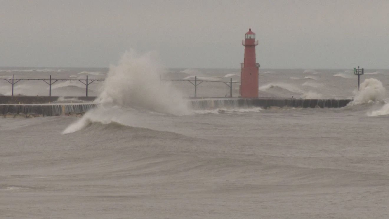 Massiva vågor slår mot fyren Algoma Pierhead Lighthouse på Michigansjön under en kraftig stormvind.