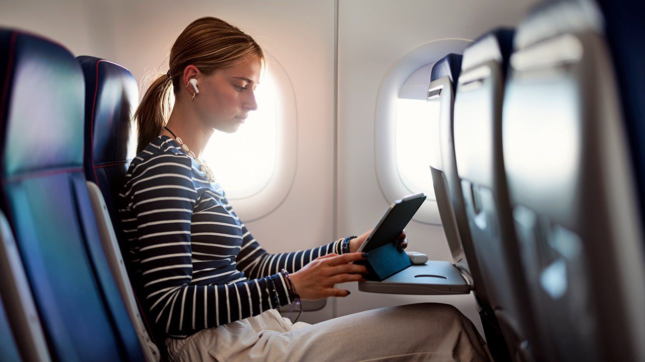 Mujer joven usando audífonos en un avión