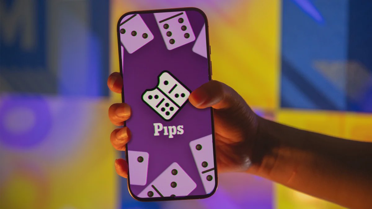 A person playing the Pips domino puzzle game on a smartphone, showing the distinctive dot patterns
