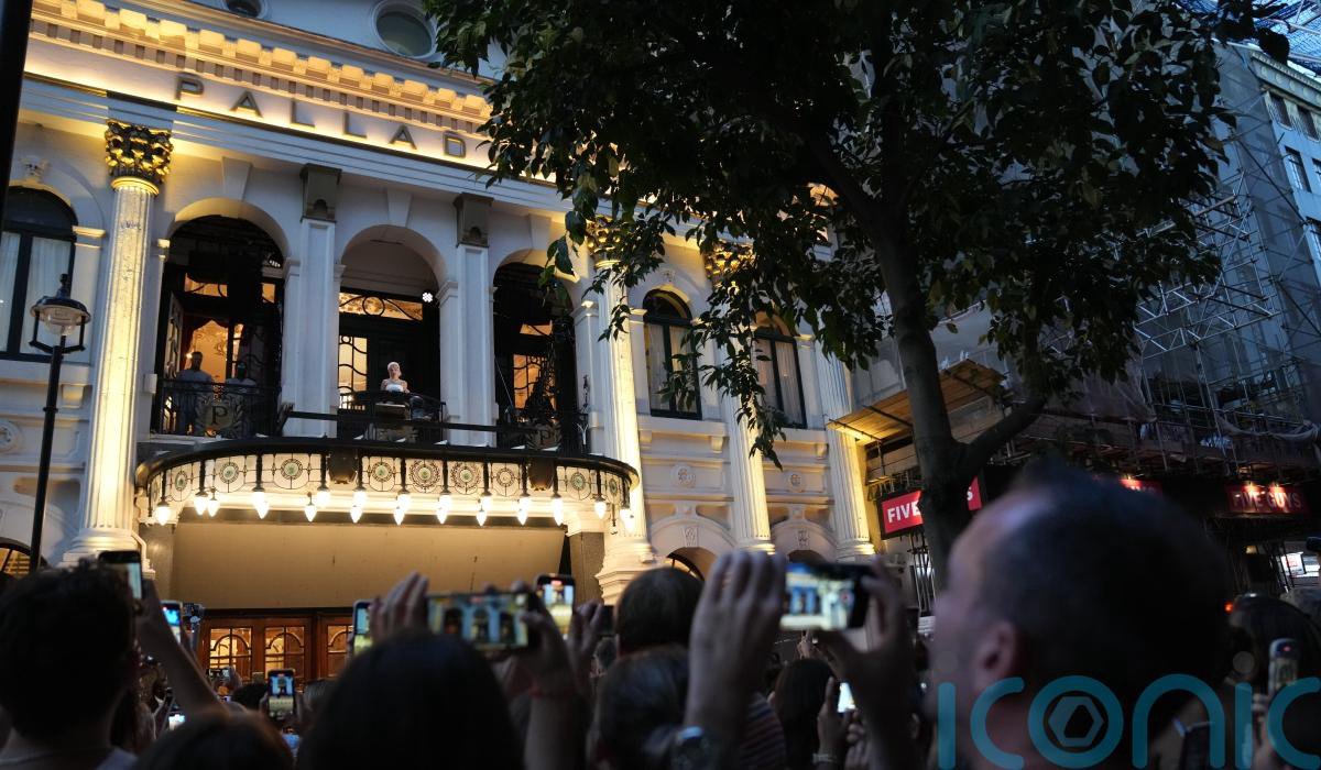 Rachel Zegler performing on a balcony for a crowd