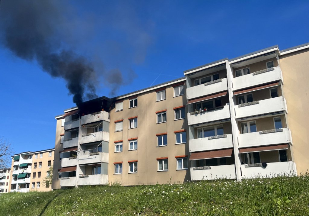 Viaturas da polícia de Basel-Landschaft e bombeiros em frente a um prédio de apartamentos