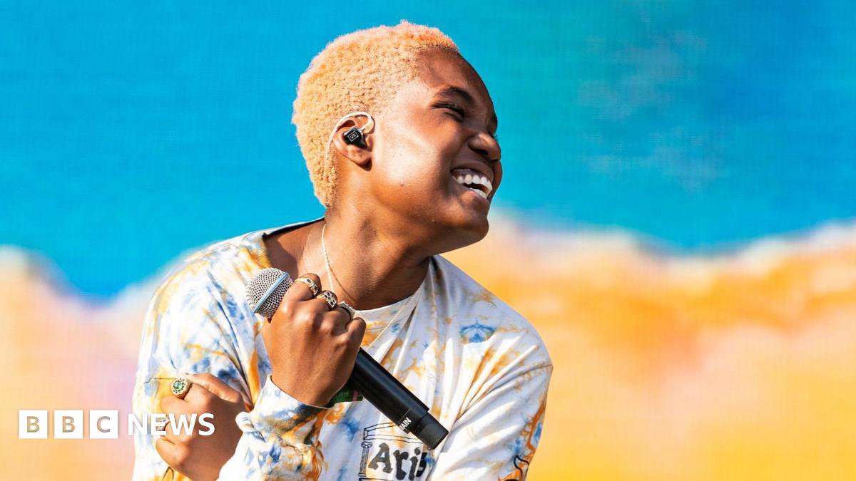 Arlo Parks performing on stage with a microphone